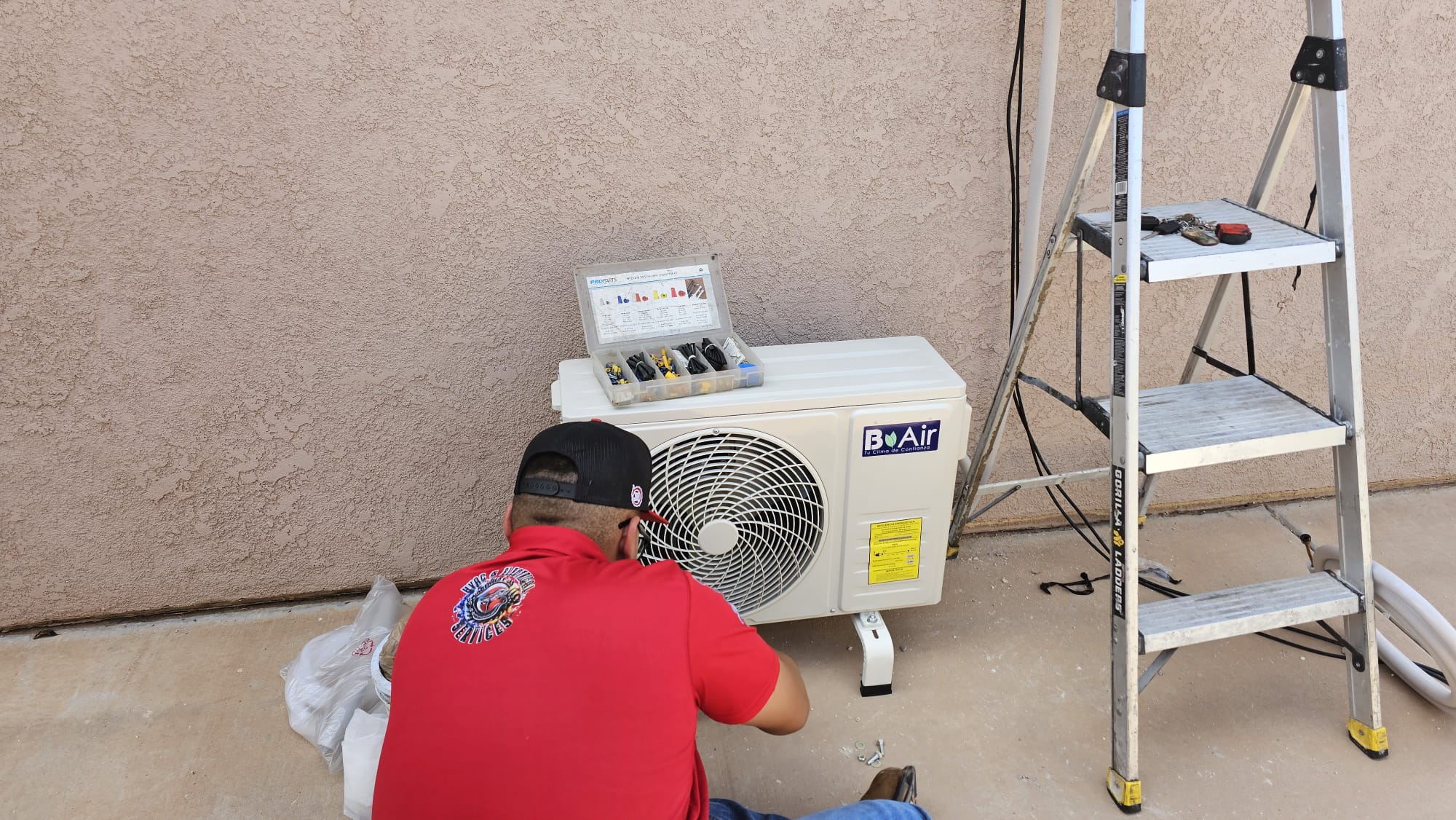 Técnico instalando una unidad condensadora de aire acondicionado junto a una escalera
